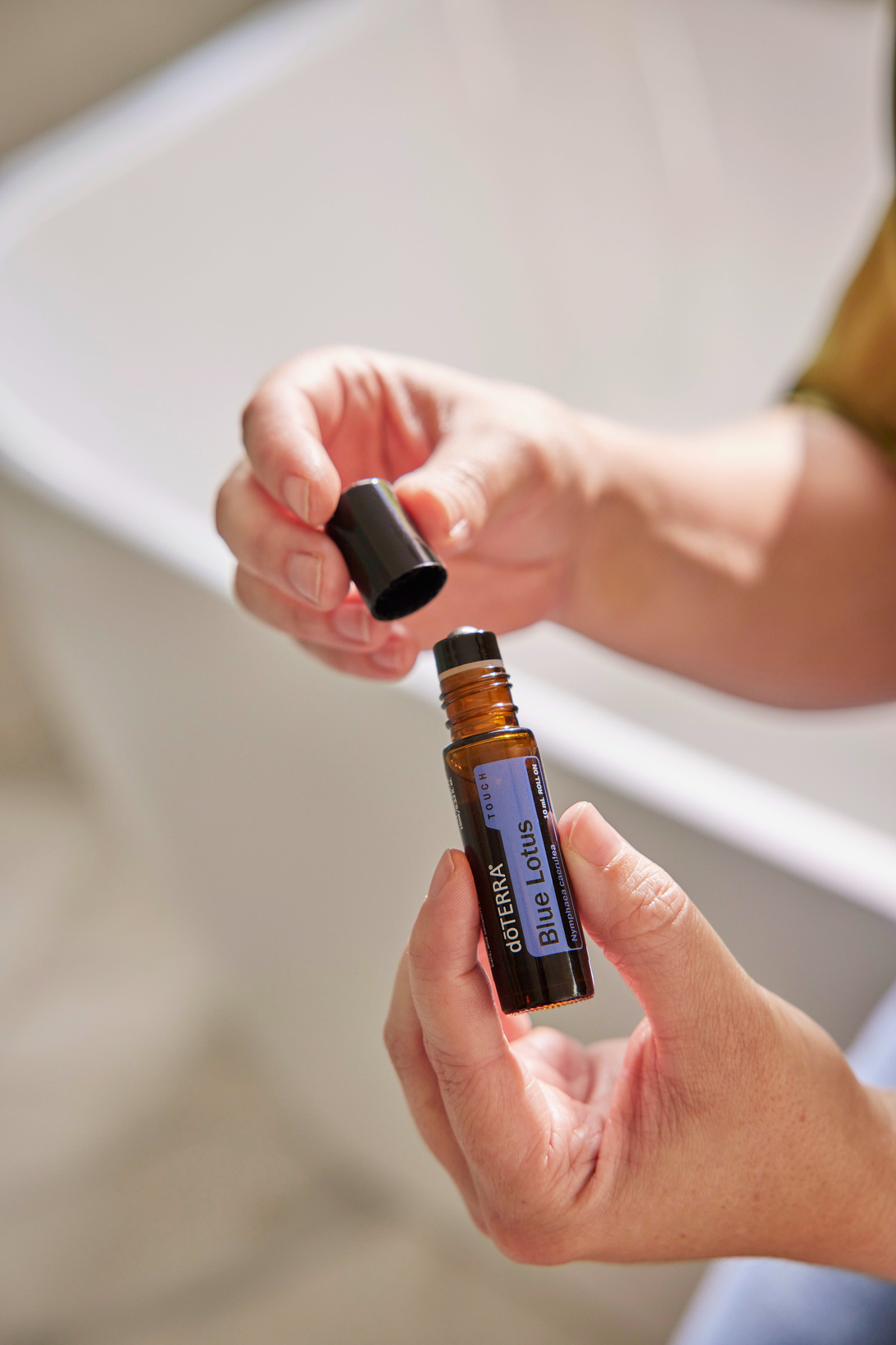 A woman holding a bottle of essential oil in her hand